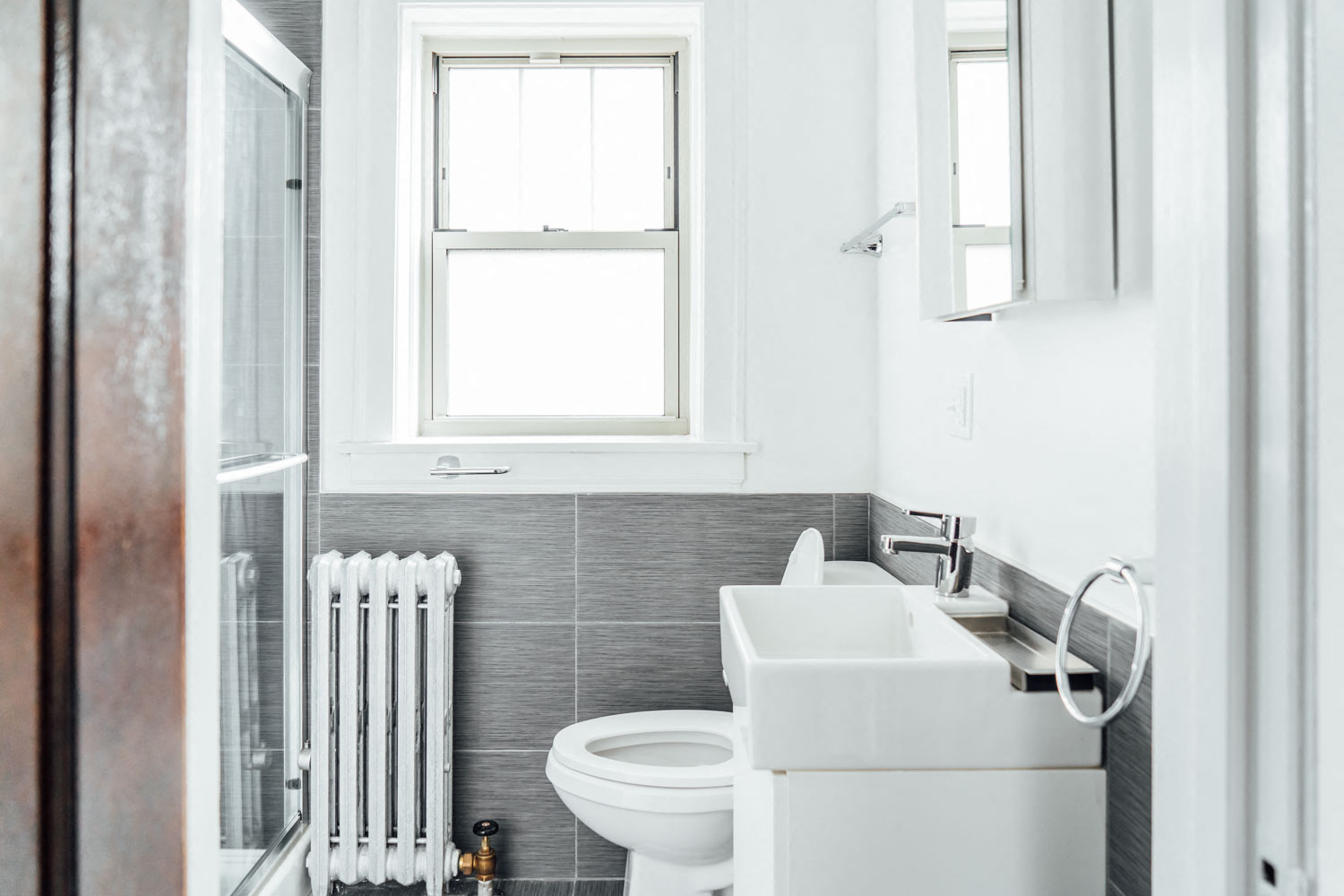 a white bathroom with a sink toilet and a window