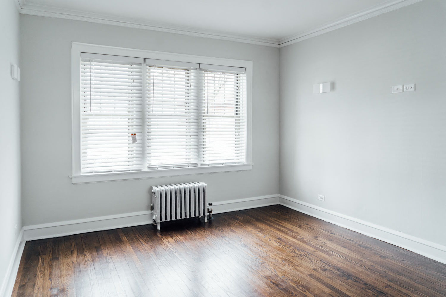 a room with wood floors and a radiator and a window
