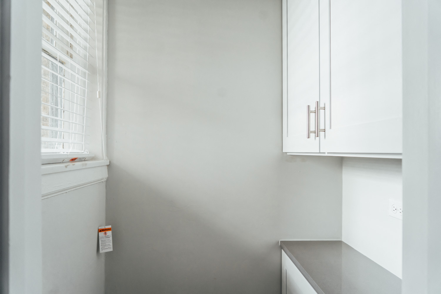 an empty kitchen with white cabinets and a window