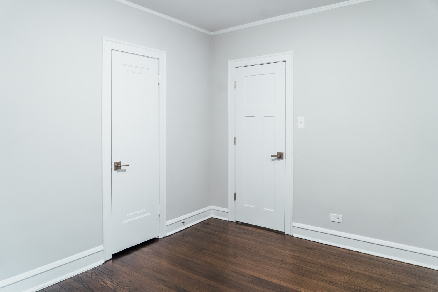 an empty room with white walls and wooden floors and two doors