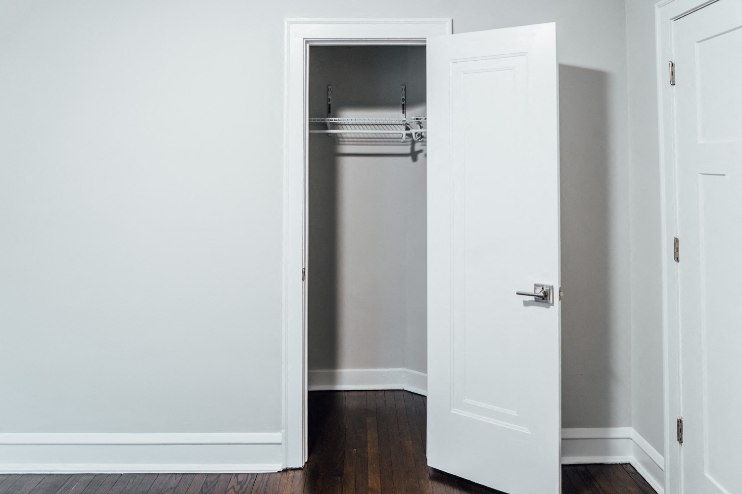 an empty closet in a room with white walls and a wooden floor