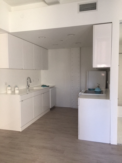 an empty kitchen with white cabinets and a sink