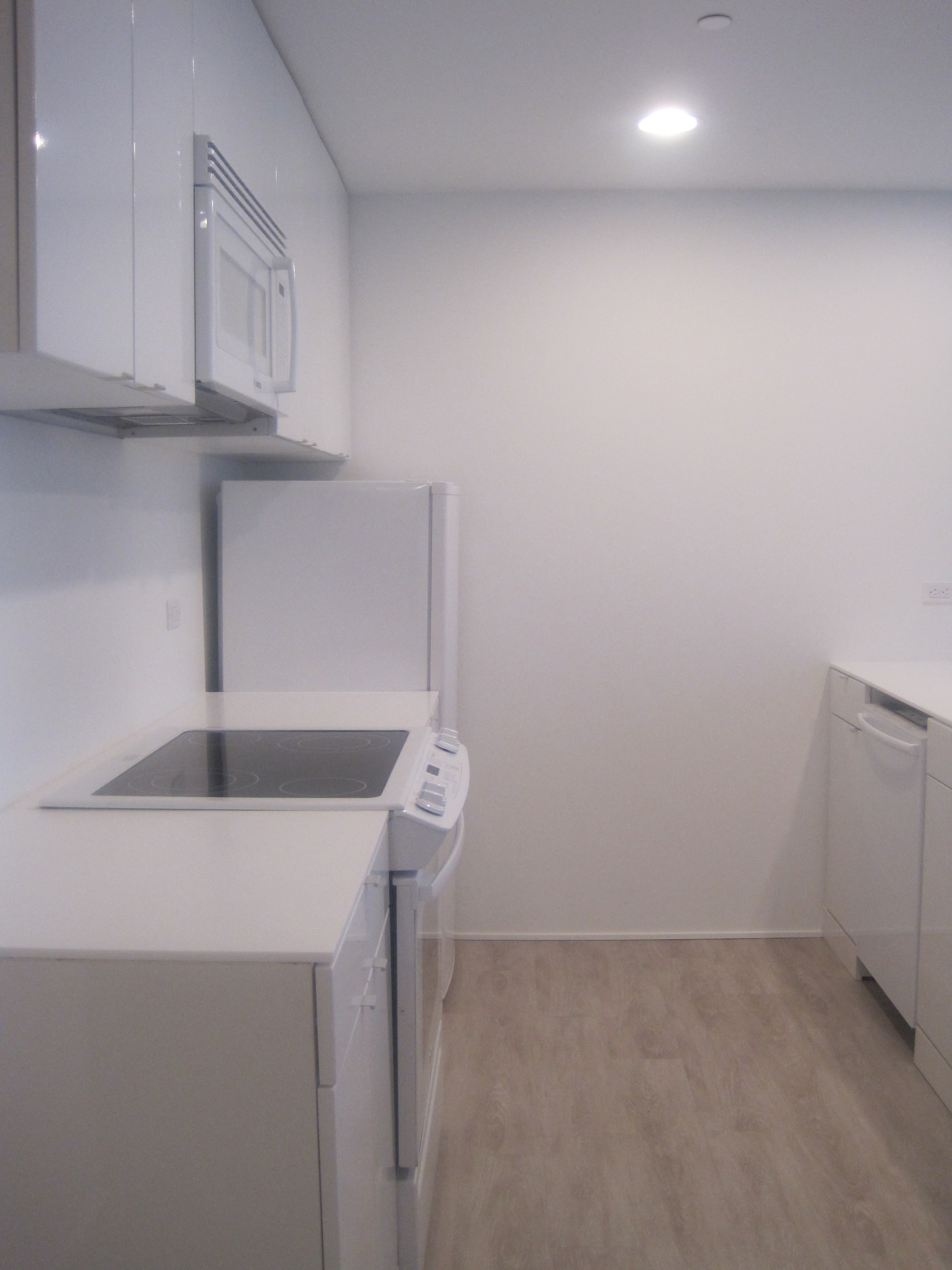 an empty kitchen with white cabinets and a refrigerator and a sink