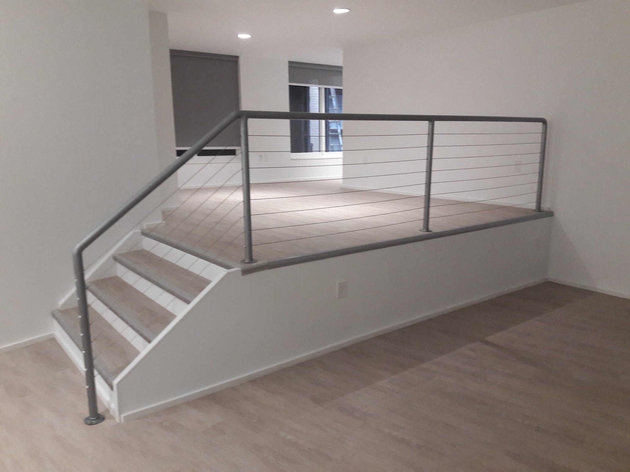 the stairway in a new home with white walls and a metal railing
