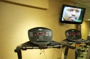 a gym with several machines and a television on the wall