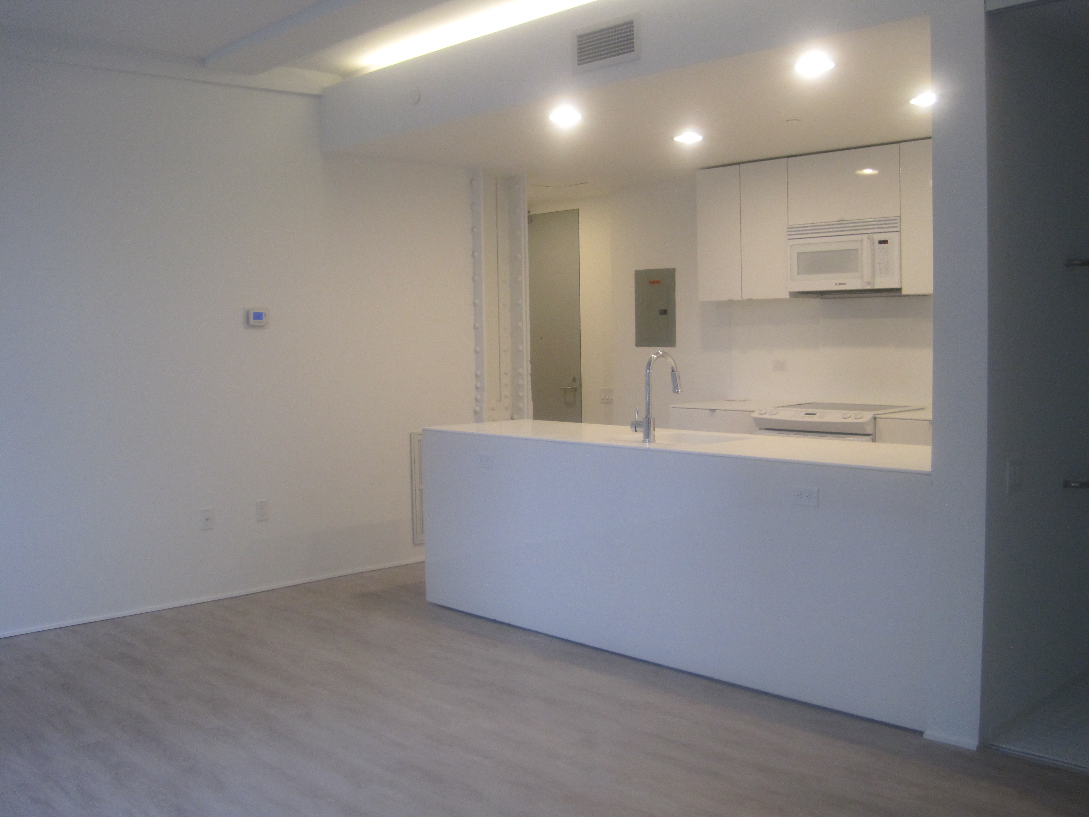 an empty room with a kitchen and a sink and a mirror