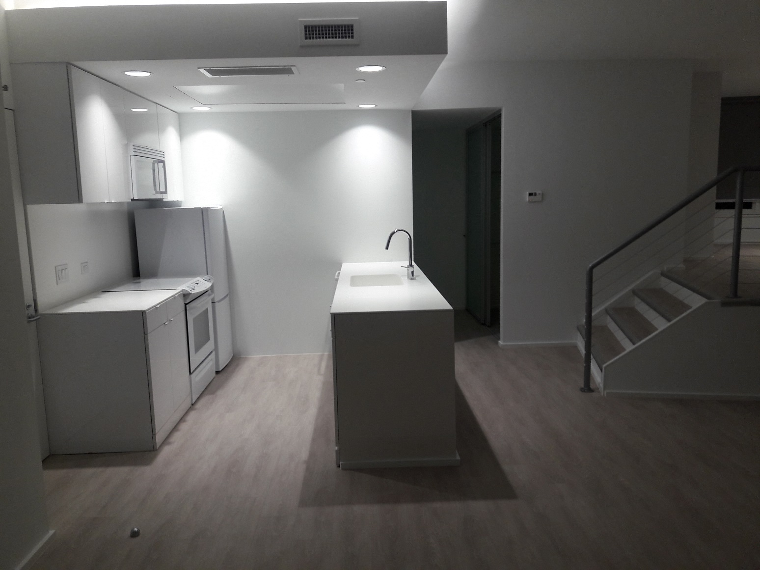 an empty kitchen with a sink and a stove and a staircase