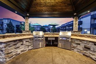 an outdoor kitchen with stainless steel appliances and a patio with umbrellas