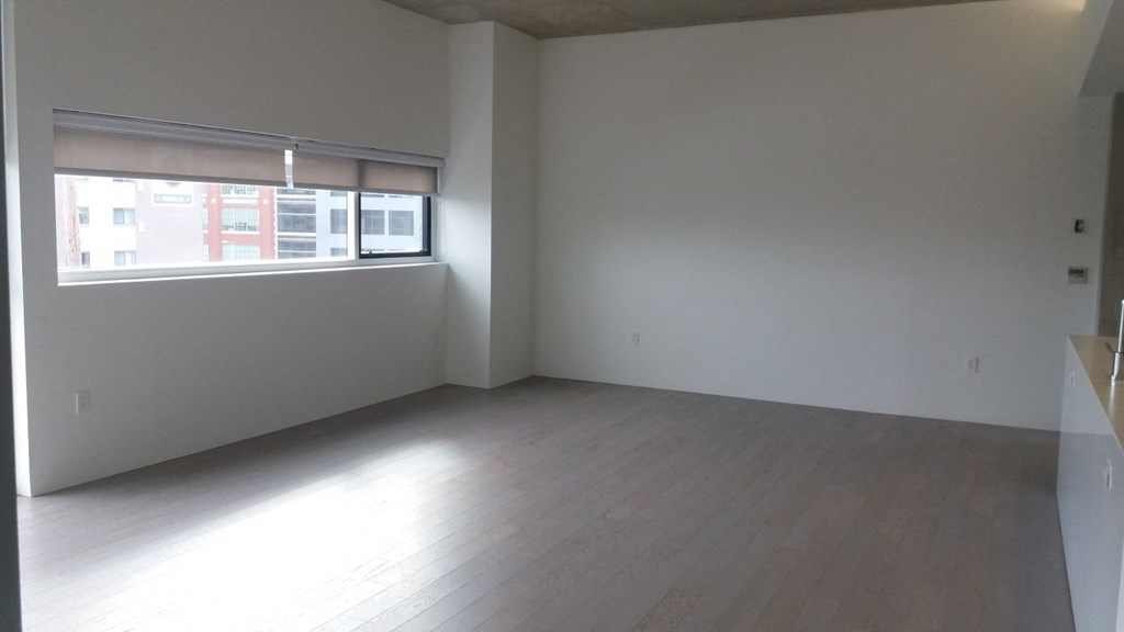 an empty living room with wood floors and a window