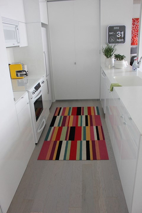 a kitchen with white cabinets and a rug on the floor