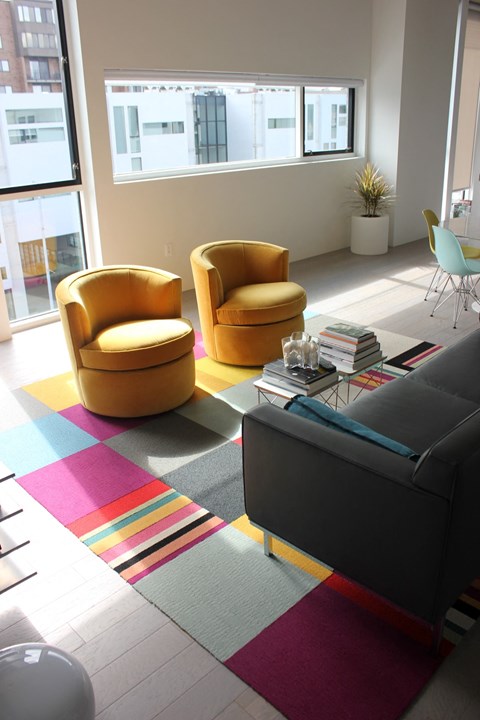 a living room with yellow chairs and a colorful rug