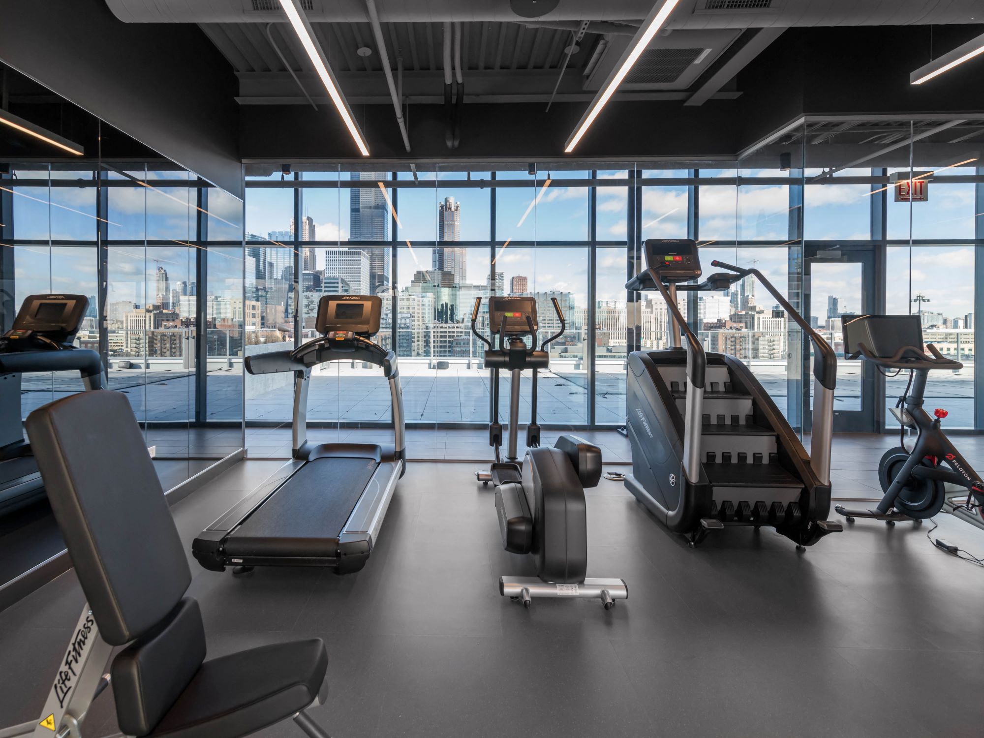 a gym with cardio equipment and a view of the city
