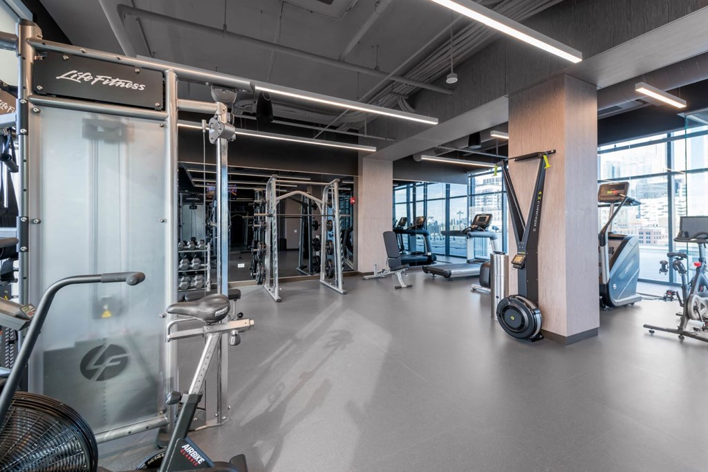 a gym with weights and cardio machines and a glass wall