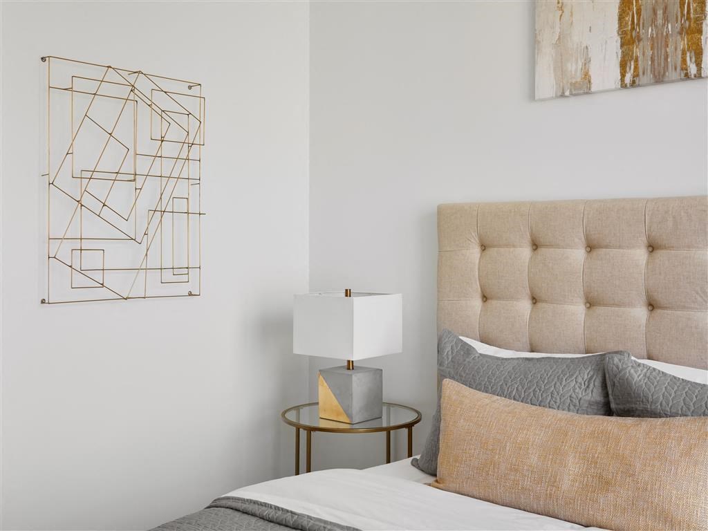 a bedroom with a bed and a lamp and a painting on the wall