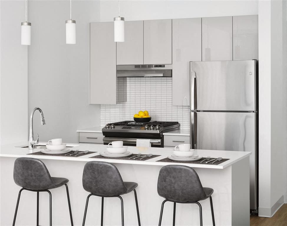 a kitchen with white cabinets and a counter with chairs