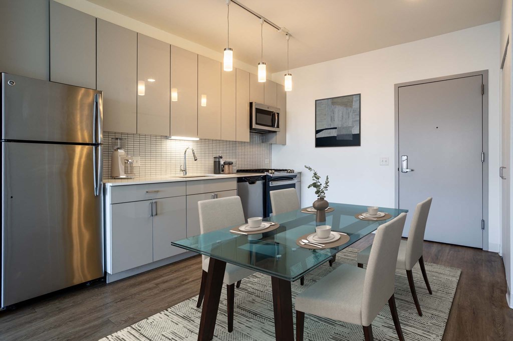 A modern kitchen with a glass dining table and chairs.
