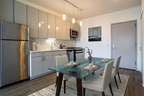 A modern kitchen with a glass dining table and chairs.