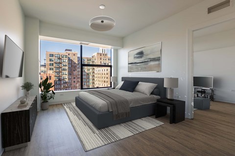 A modern bedroom with a large bed and a view of the city.