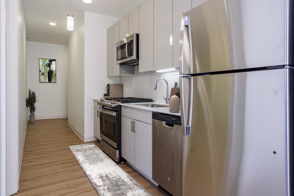 A modern kitchen with stainless steel appliances and wooden flooring.