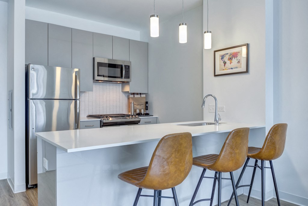 a kitchen with stainless steel appliances and a bar with three stools