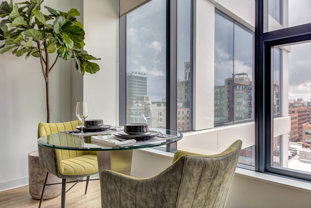 a dining area with a glass table and chairs and a view of the city