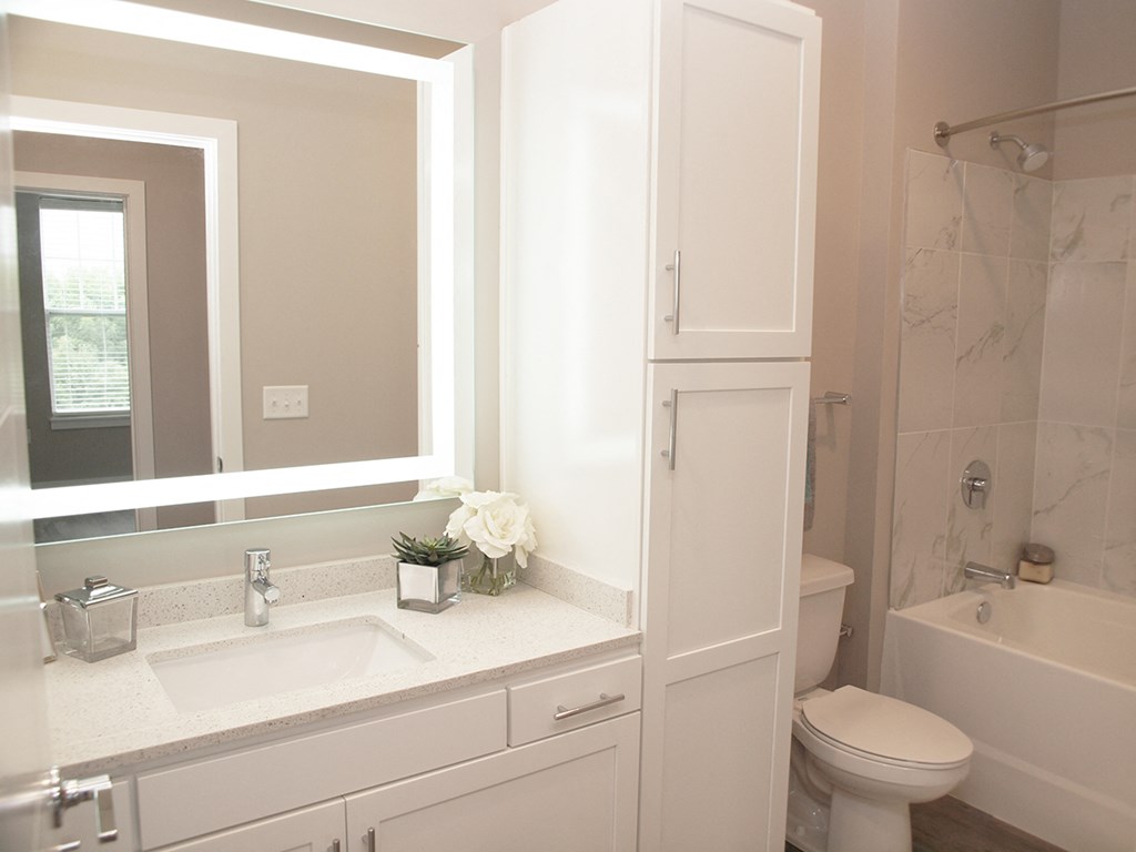 a white bathroom with a mirror and a sink and a toilet