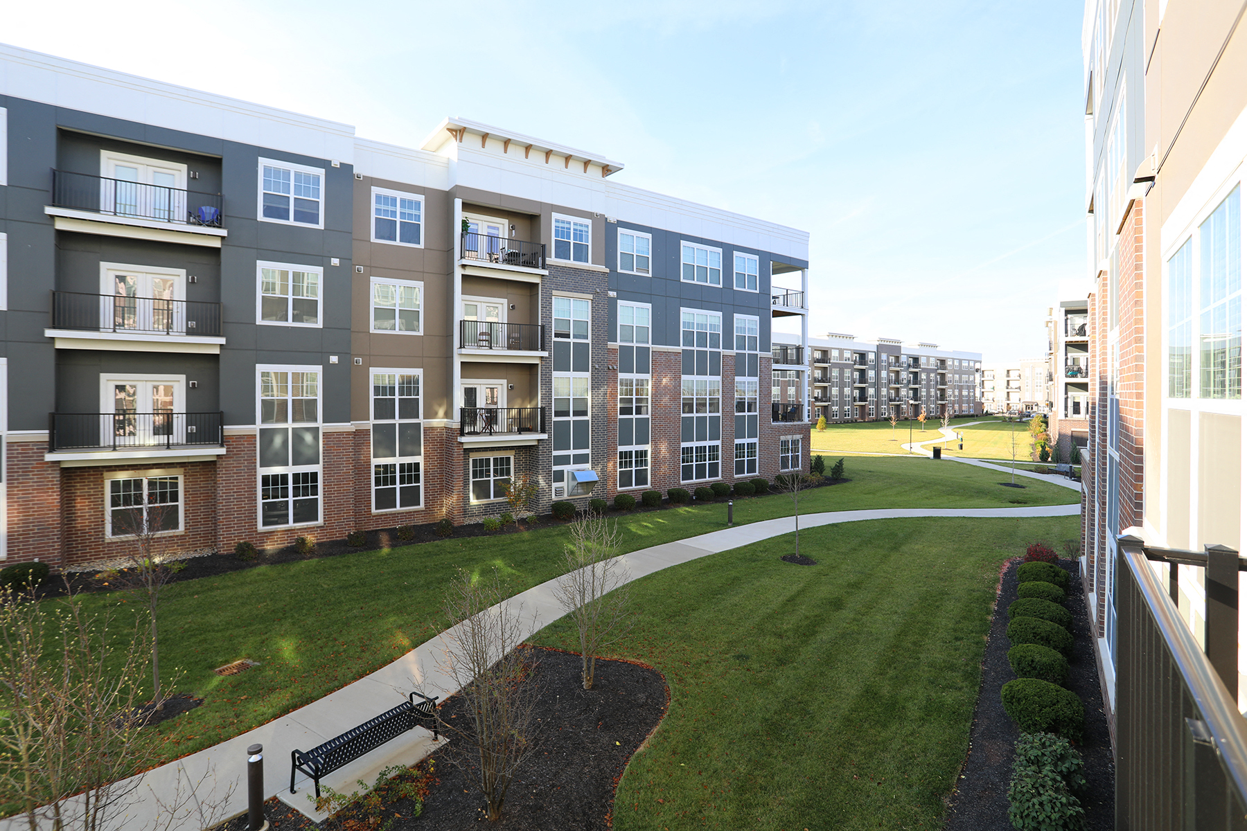 an exterior view of an apartment building with a grassy courtyard