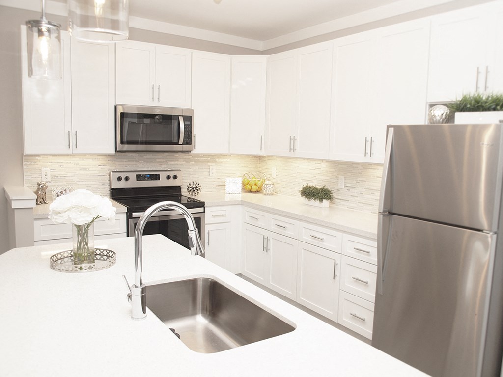 a white kitchen with stainless steel appliances and white cabinets