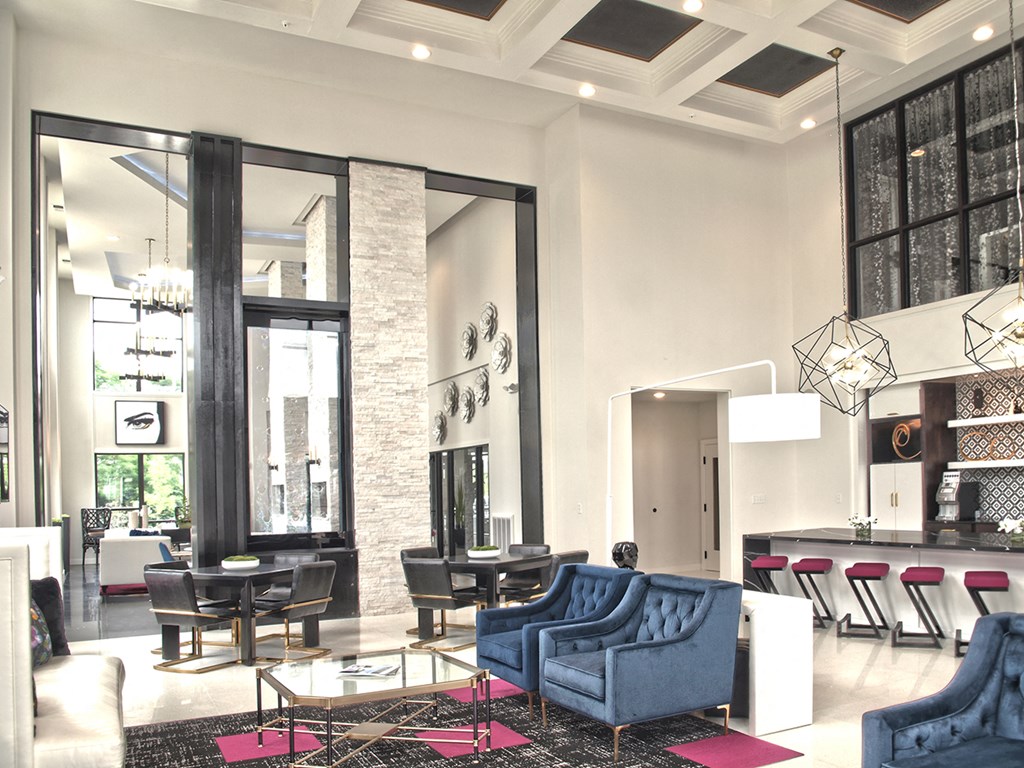 a living room with blue couches and chairs and a dining room with a table