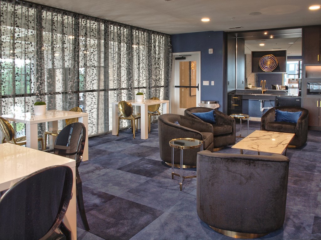 a room with couches chairs and tables and a kitchen