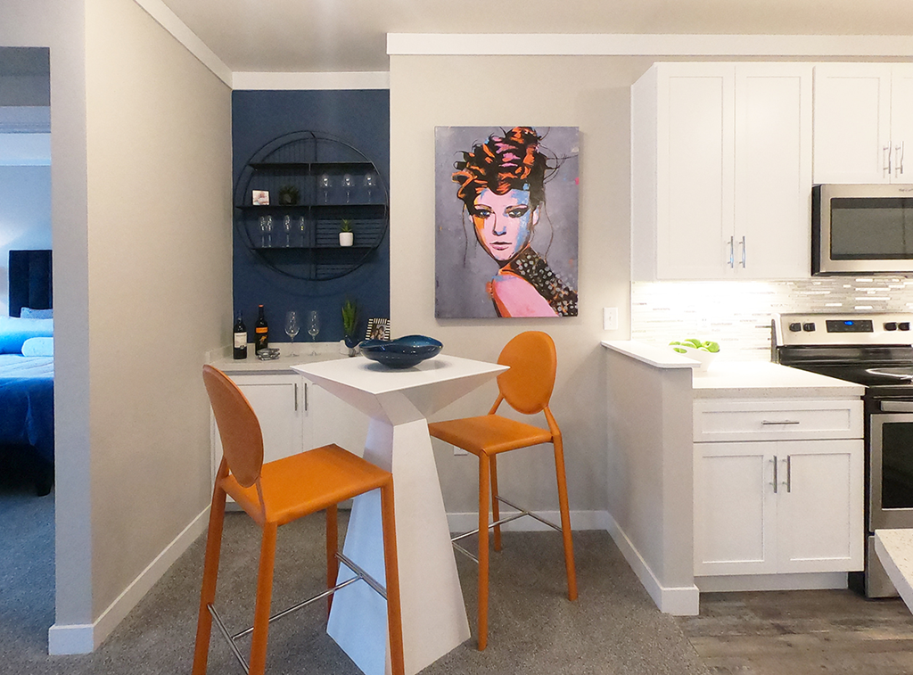 a kitchen with a table and two chairs and a painting on the wall