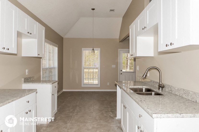 an empty kitchen with white cabinets and a sink