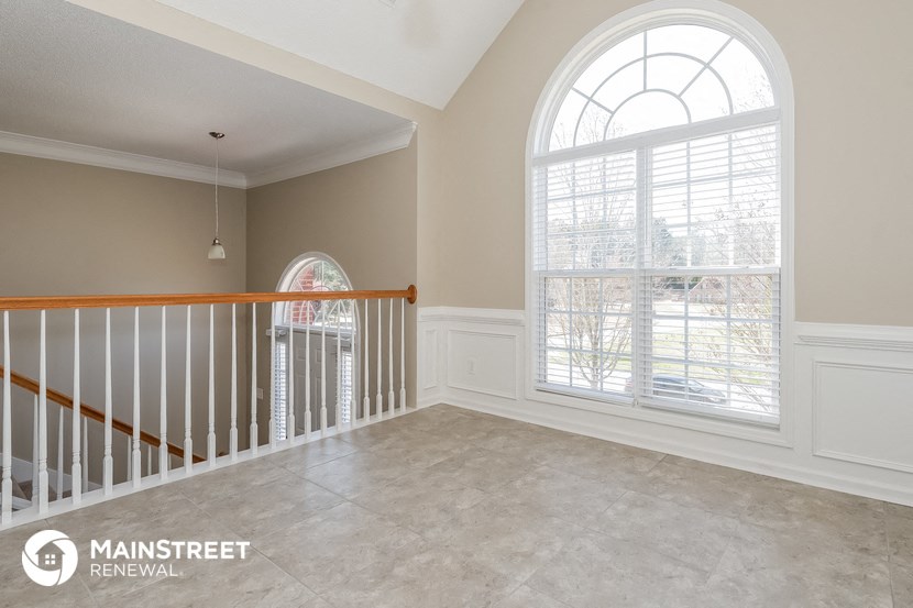 a living room with a staircase and a large window