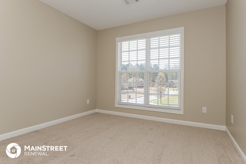 a bedroom with a large window and a carpeted floor