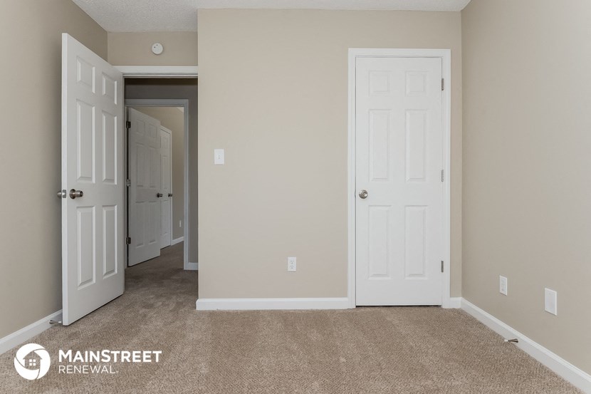 a bedroom with two doors and a carpeted floor    and a closet