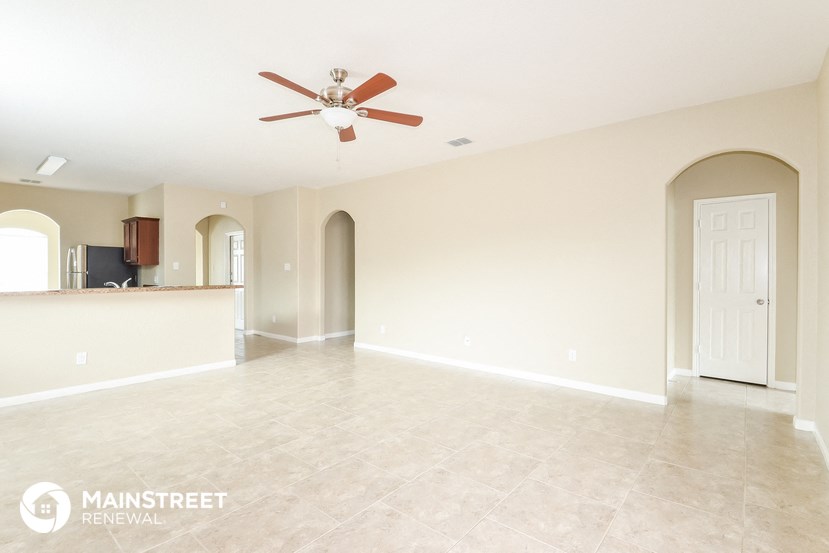 an empty living room with a ceiling fan