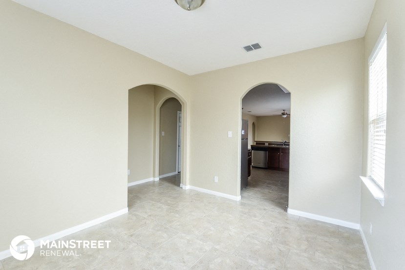 an empty living room with a hallway and a kitchen