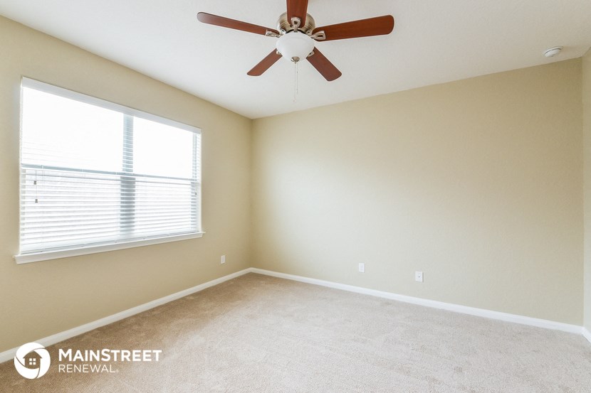 a bedroom with a ceiling fan and a large window
