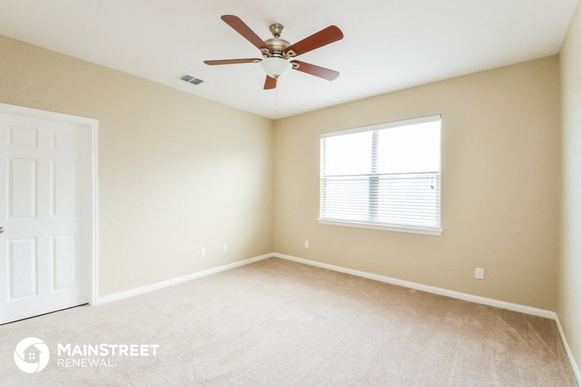 an empty room with a ceiling fan and a window