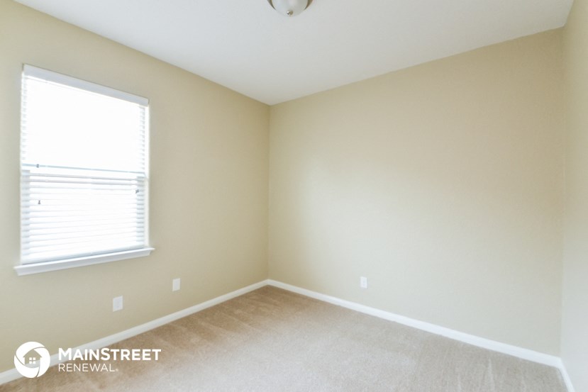 a bedroom with a large window and beige walls and carpet