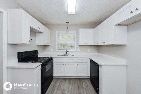 a white kitchen with black appliances and white cabinets