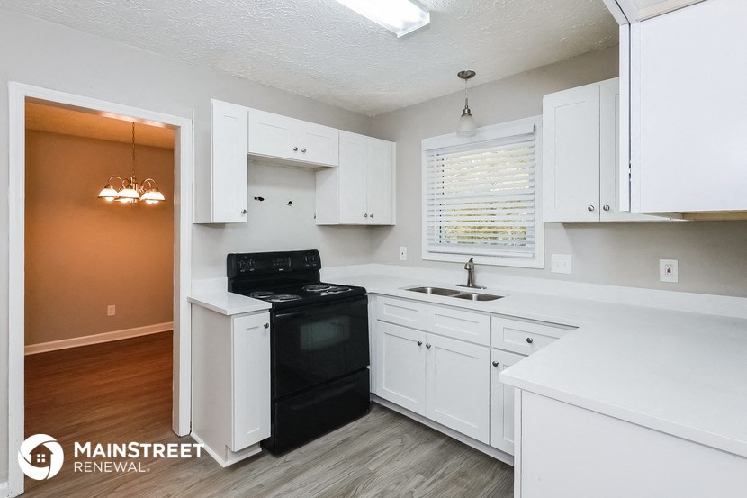 a white kitchen with black appliances and white cabinets