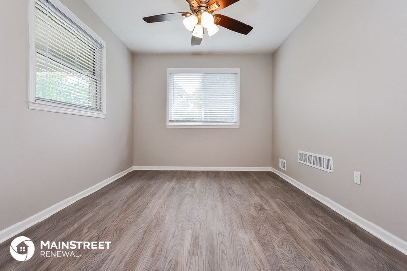 the spacious living room with wood flooring and a ceiling fan