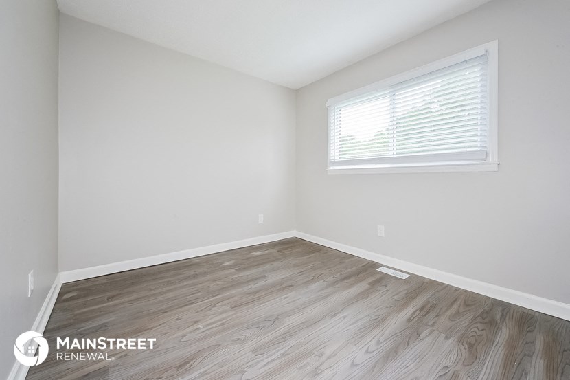 the upstairs bedroom with wood flooring and a window