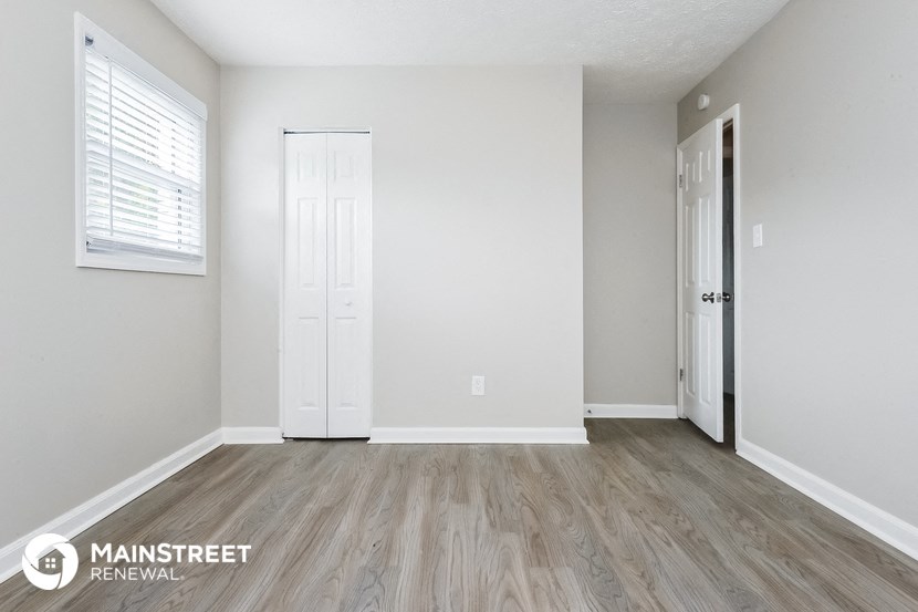 the spacious living room with white walls and wood flooring