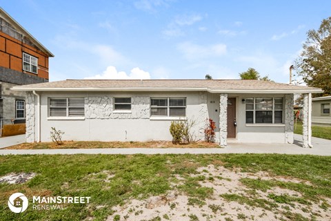 the front of a white house with a yard and grass