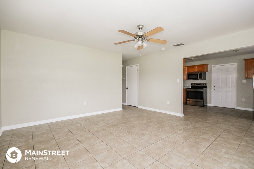 the spacious living room with tile flooring and a ceiling fan