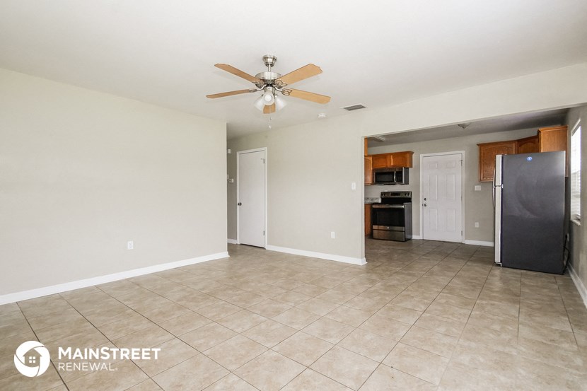 the living room is spacious with tile flooring and a ceiling fan