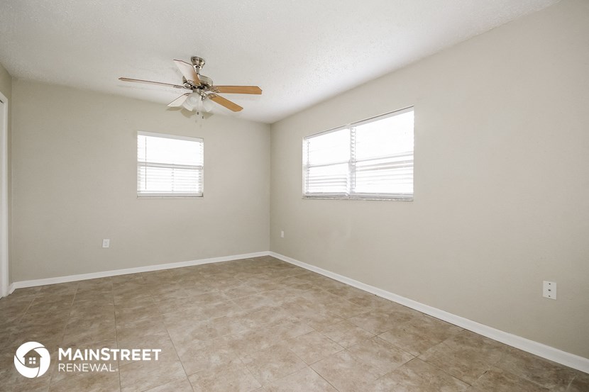 the spacious living room with ceiling fan and tile flooring