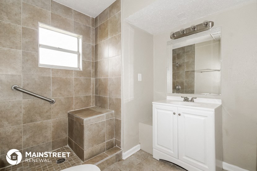 a small bathroom with a shower and a sink and a mirror